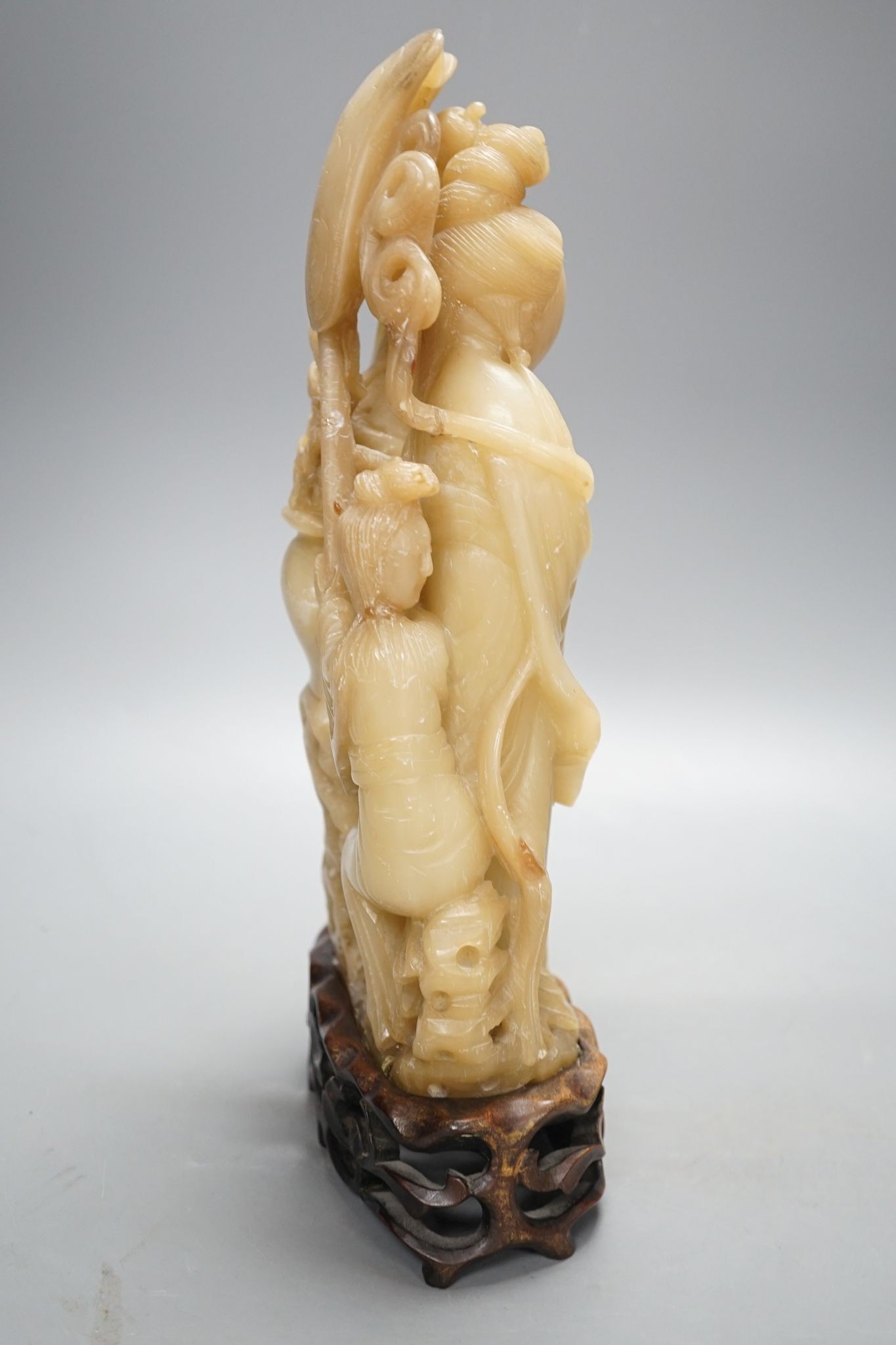 A Chinese soapstone carving of two ladies, wood stand, early 20th century, 36 cms high.